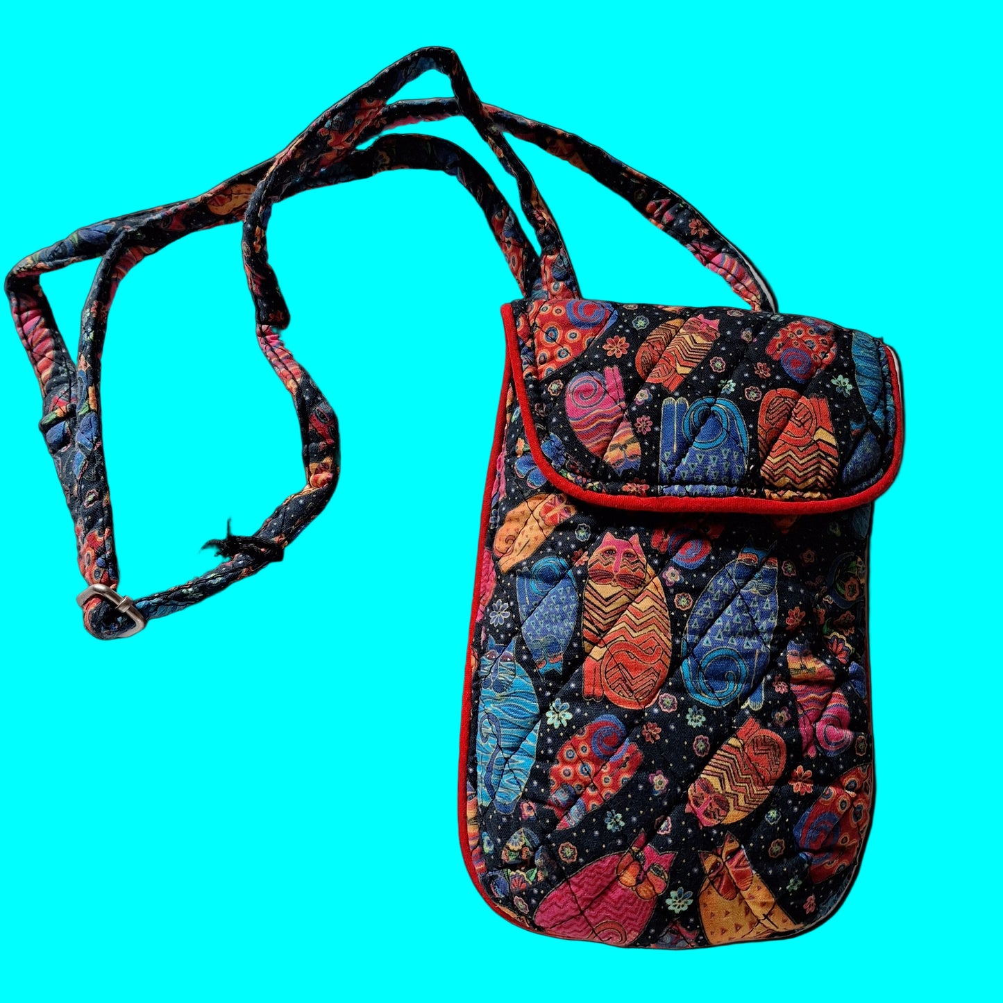 Colorful feline patterned handbag with a strap on a turquoise background