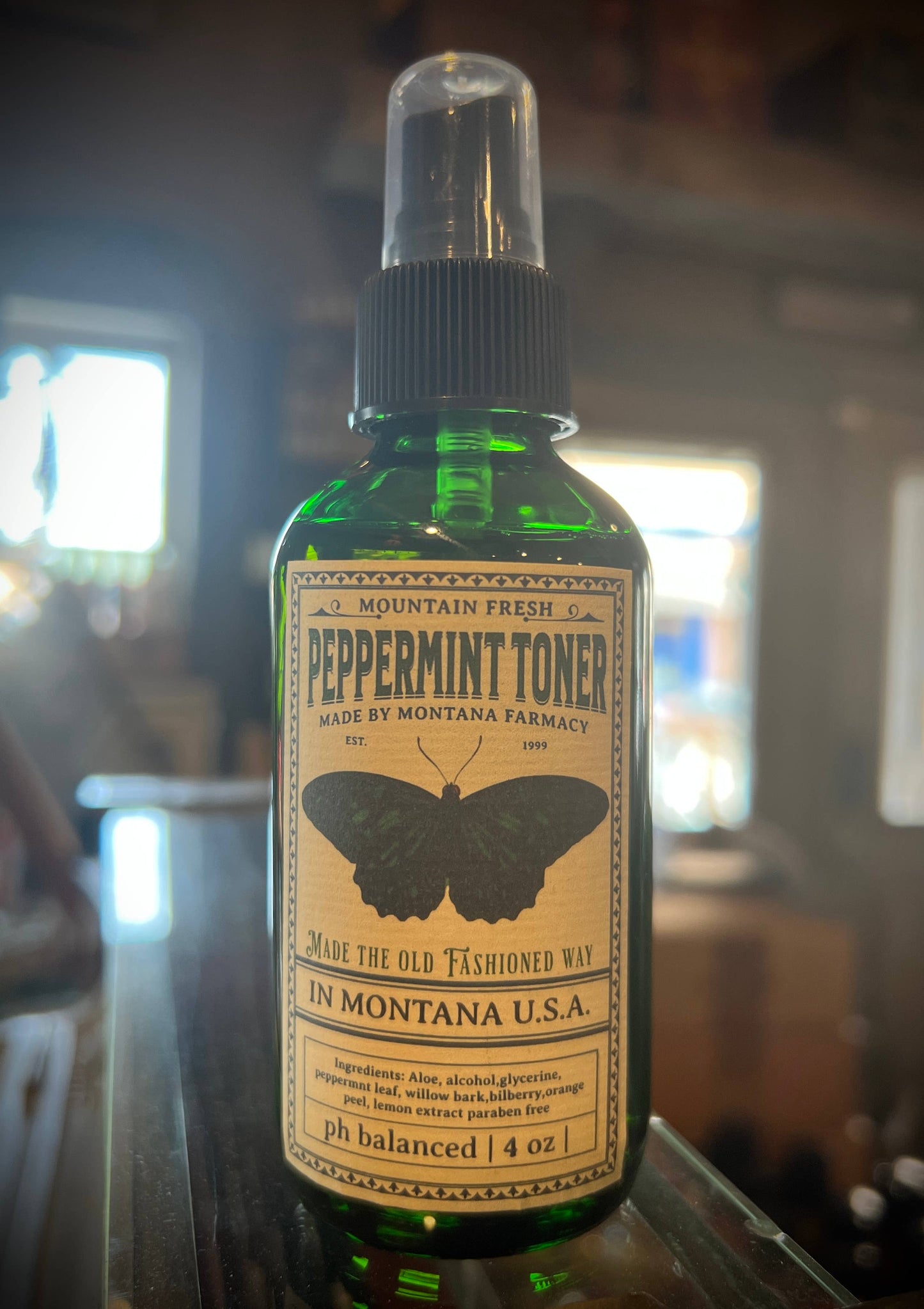 Green bottle of peppermint toner with a label on a blurred background