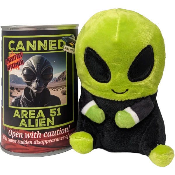 A green alien plush toy next to its branded silver can packaging. The plush has a bright lime green head and feet, black eyes, and a black body with white cuffs. All on a white background