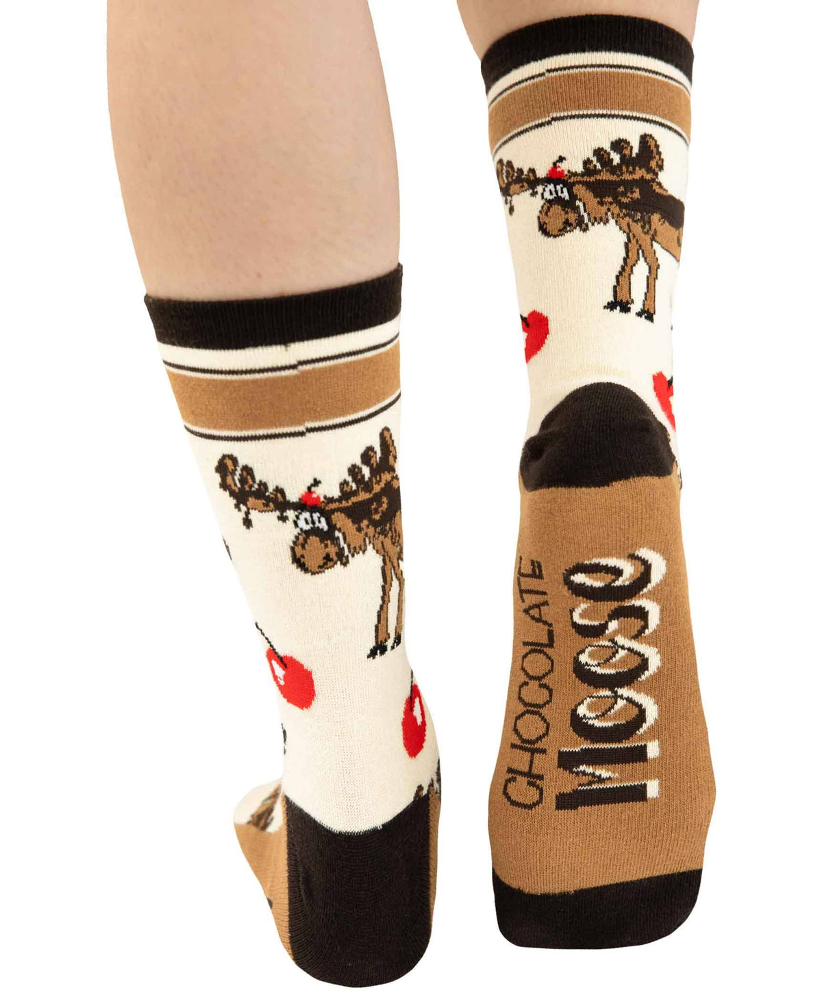 A pair of novelty crew socks shown on a person's feet against a white background. The socks feature a brown moose graphic on a cream base, with black and tan stripes at the top, red hearts, and the word 'CHOCOLATE moose' printed vertically on the sole.