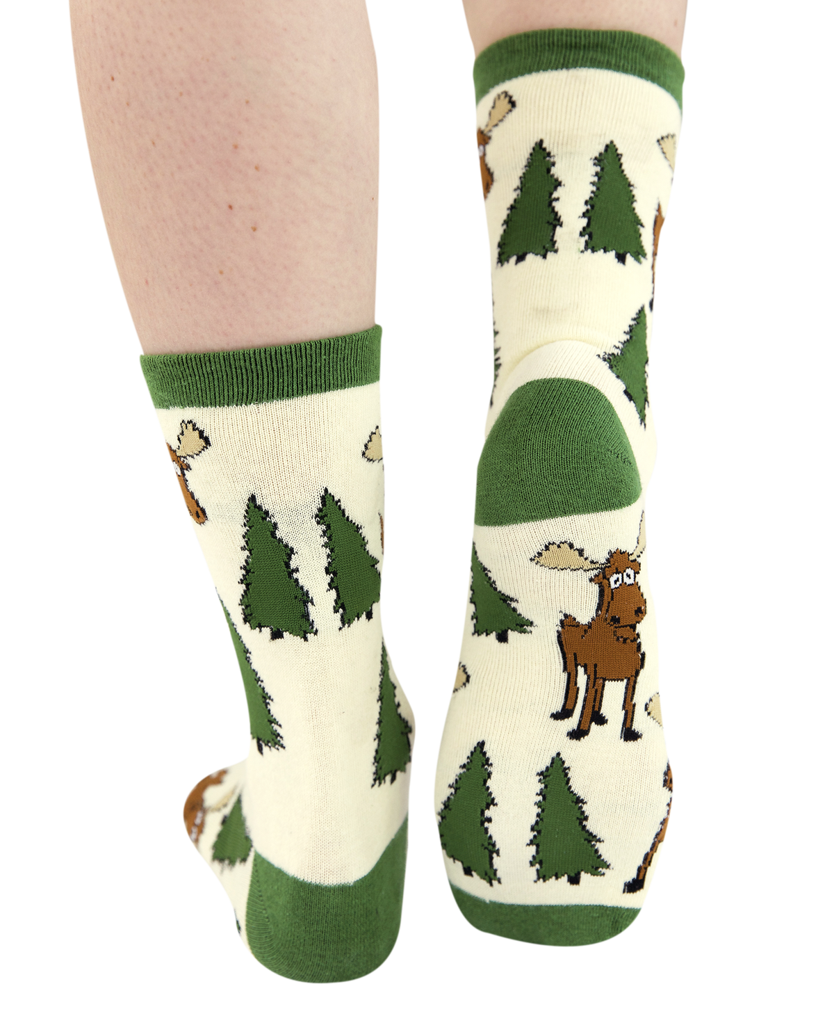 A pair of cream-colored crew socks with green cuffs, heels, and toes, featuring a woodland pattern of pine trees and a moose . The socks are shown on a person's legs against a plain white background