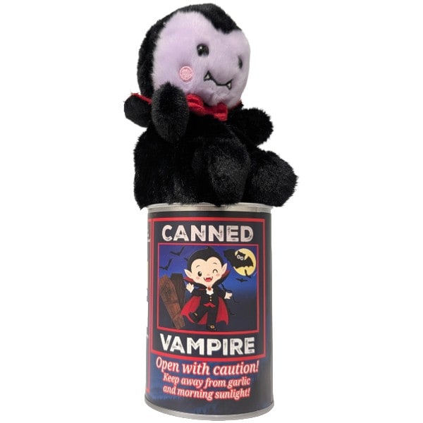 A plush vampire toy with black fur, a pale pinkish-purple face, and a red bow tie, sitting on top of a labeled can that reads 'CANNED VAMPIRE' with a cartoon vampire illustration.